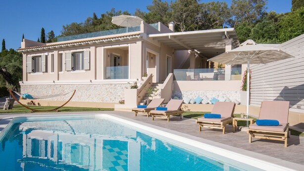Una villa moderna con piscina, lettini prendisole e un'amaca.