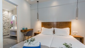 Camera d'albergo moderna con un letto grande, una testiera in legno, comodini e una piccola zona salotto con una poltrona.