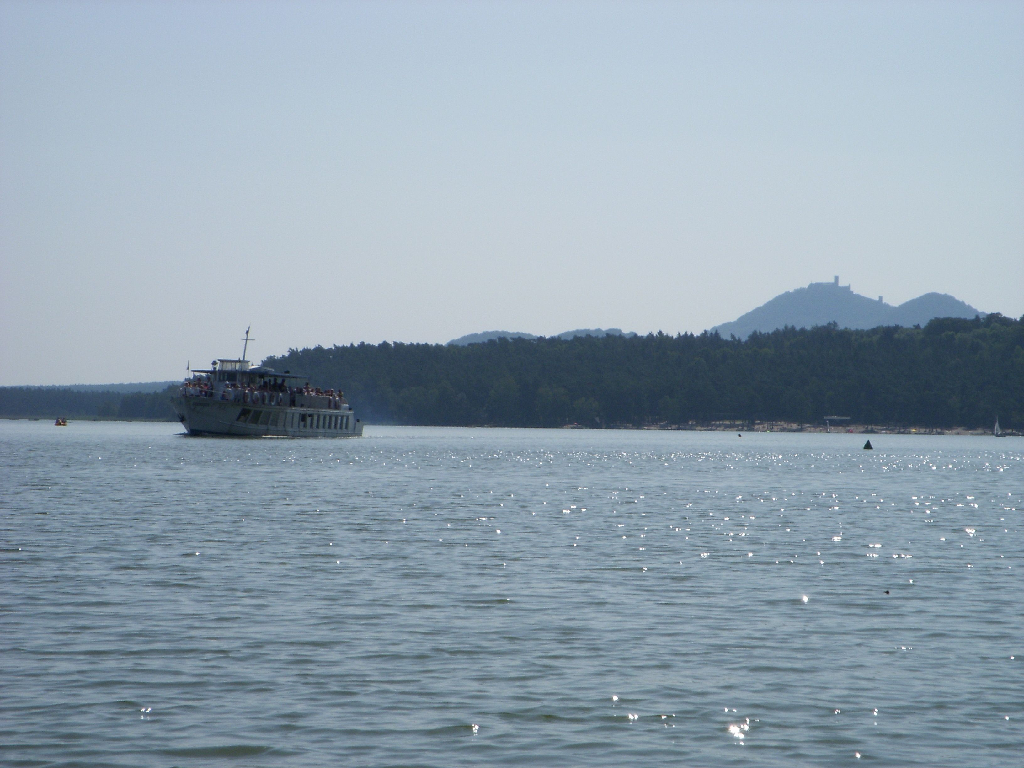 Un barco sobre un cuerpo de agua tranquilo con una colina boscosa al fondo.