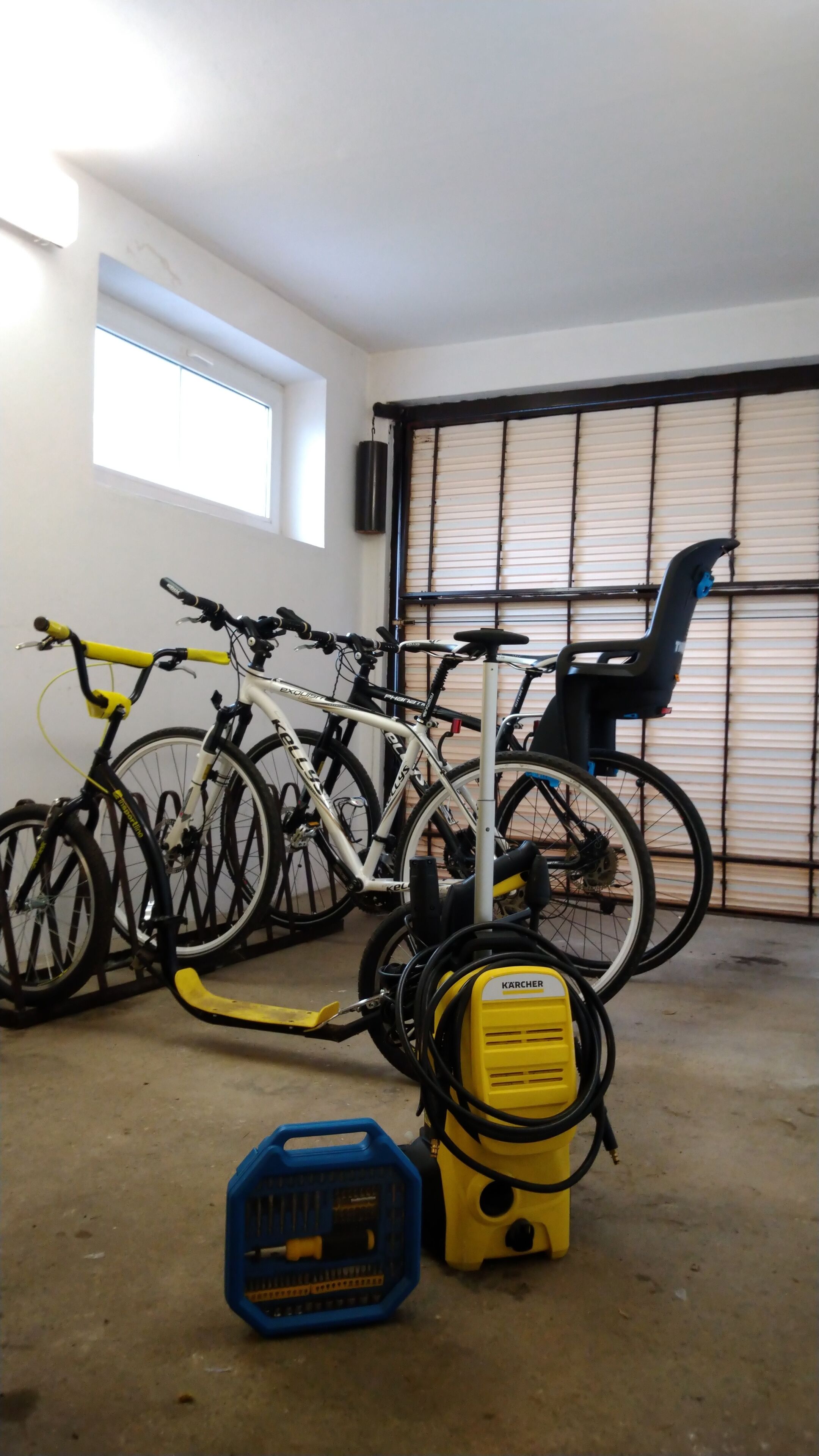 Ett garage med cyklar och en gul KÄRCHER-cykelpump.