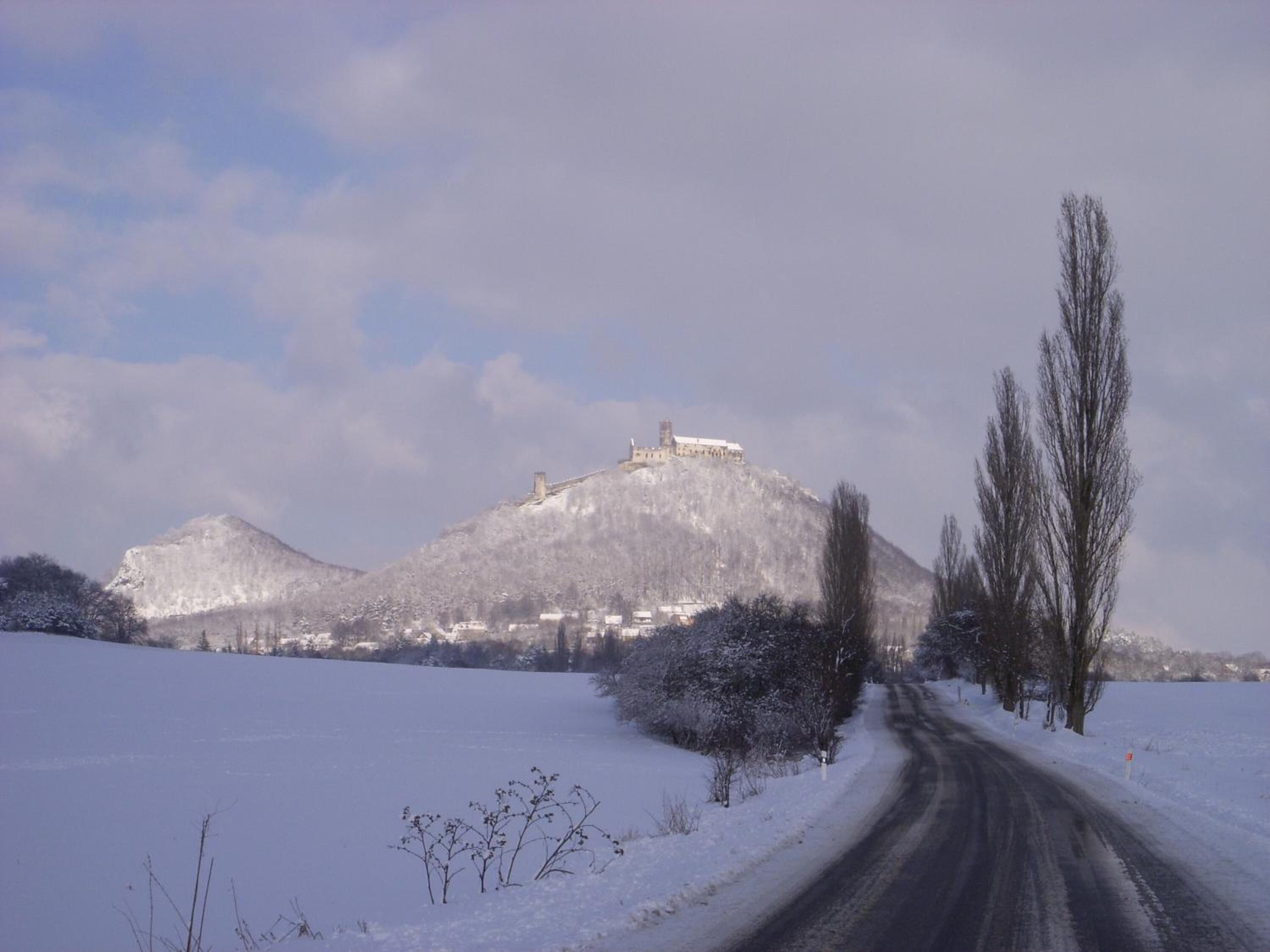 Un paysage enneigé avec une route menant à un château perché sur une colline.