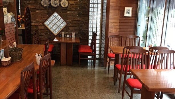 Ein Restaurant mit Holztischen und -stühlen, einer Steinwand und einem großen Fenster mit Strukturglas.