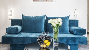 A modern living room with a teal sofa, a glass coffee table with fruit, and two wall-mounted light fixtures. - Krakow B&B Luxury Old Town (Kraków)