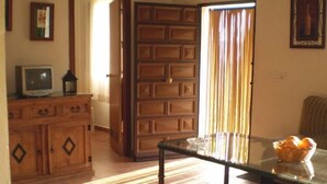 Un salon comprenant un canapé, une table basse avec un plateau en verre, un meuble en bois, un téléviseur et un lustre.