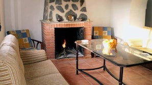 Un salon chaleureux avec une cheminée en pierre, une table basse en verre et un canapé à rayures.