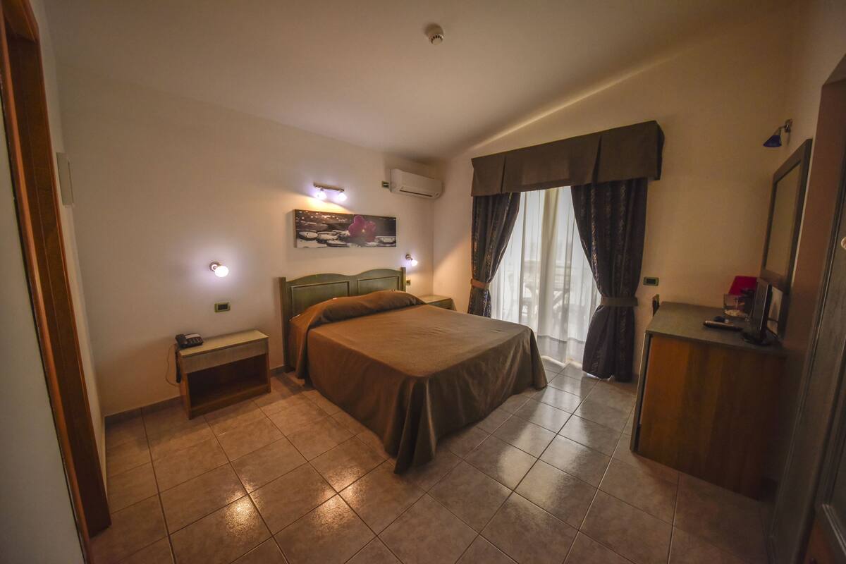 Una habitación de hotel con cama, mesita de noche y escritorio con silla.