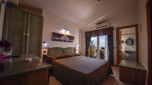 Ett hotellrum med en säng, ett skrivbord, en stol, en garderob och ett badrum med handfat och spegel.