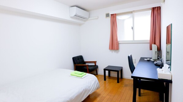 Une petite pièce propre, avec un lit, un bureau, une chaise et une fenêtre avec des rideaux.