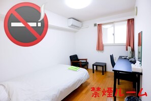 Une chambre d’hôtel avec un lit, un bureau, une chaise et une fenêtre avec des rideaux.