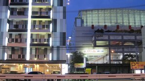 A multi-story hotel with balconies, a parking sign, and a large glass building in the background. - Hotel Chuo Selene (Osaka)