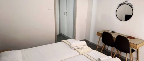 A hotel room with a bed, a desk with a chair, a TV, and a mirror.