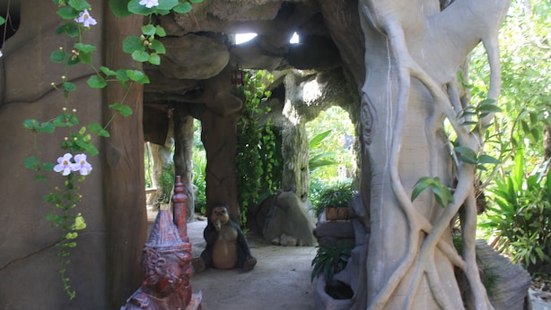 A garden with a stone pathway, a large tree, and a statue. - Jorakae Sampan Resort (U Thong)