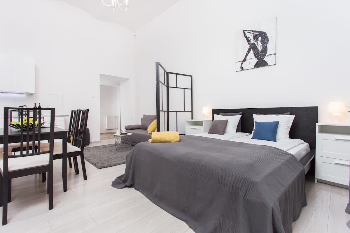 Quarto moderno com cama grande, mesas de cabeceira, escrivaninha e uma cadeira.