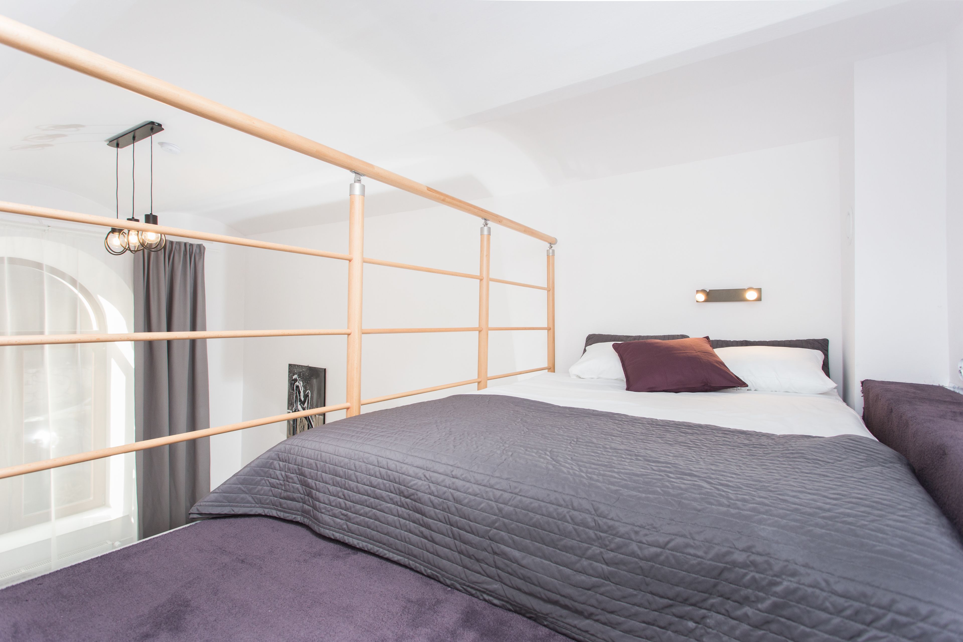 A modern hotel room with a large bed, a wooden headboard, a mirror, and a small bedside table.