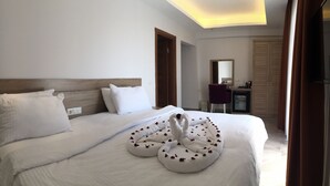 A hotel room with a neatly made bed, a desk with a chair, and a mirror. - Pegasus Hotel & Villa (Fethiye)