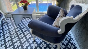 A room with a large window, a blue sofa, a small table with a potted plant, and patterned floor tiles. - Pegasus Hotel & Villa (Fethiye)