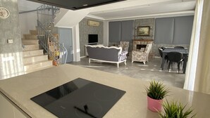A modern kitchen with a central island, a dining area with a table and chairs, and a living room with a sofa and armchairs. - Pegasus Hotel & Villa (Fethiye)