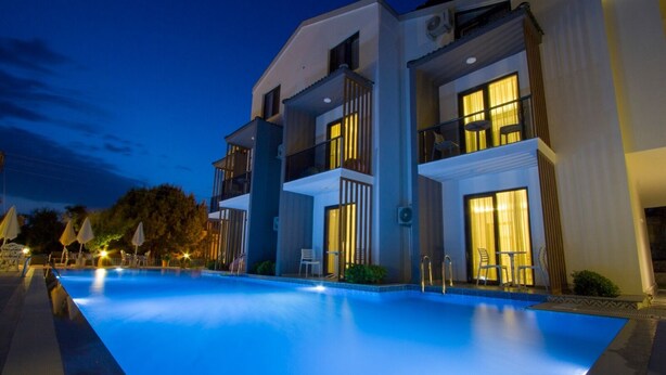 A modern hotel with a swimming pool, multiple balconies, and well-lit windows. - Pegasus Hotel & Villa (Fethiye)