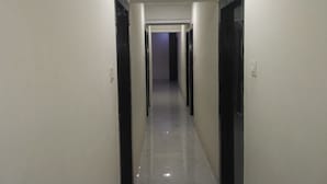 A narrow, well-lit hallway with doors on both sides leading to other rooms. - Swagatham Lodging (Navi Mumbai)