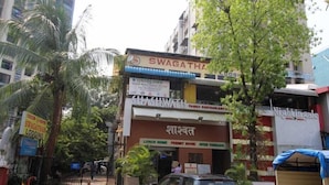 A building with a sign for 'Swagatham Lodging' and 'Nighingale Restaurant'. - Swagatham Lodging (Navi Mumbai)