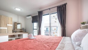 A bedroom with a large bed, a wooden wardrobe, a mirror, and a window with curtains. - Supirum Cozy Home 3 Bedroom near Beach (Thep Krasattri)