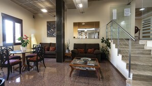A modern living room with a glass coffee table, a sofa, and a dining area with chairs. - Hotel Anna (Cocentaina)