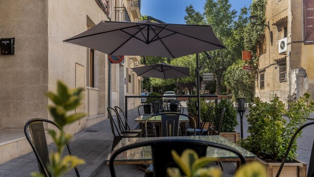 An outdoor café with tables and chairs, umbrellas, and potted plants. - Hotel Anna (Cocentaina)