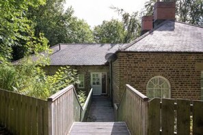 Un bâtiment en briques avec un escalier en bois menant à une porte.