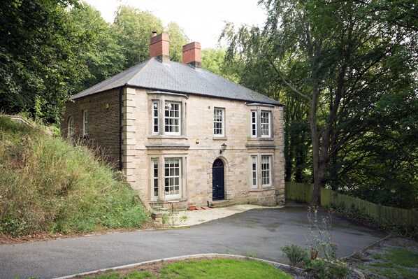A two-story stone house with a central entrance, surrounded by a garden and a fence. - Toast Lettings | Apartment 4 The Grove minutes walk from Durham City (Durham)