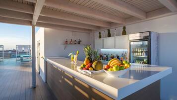 Una cocina moderna con una isla grande, un refrigerador y una zona de bar con botellas y frutas.