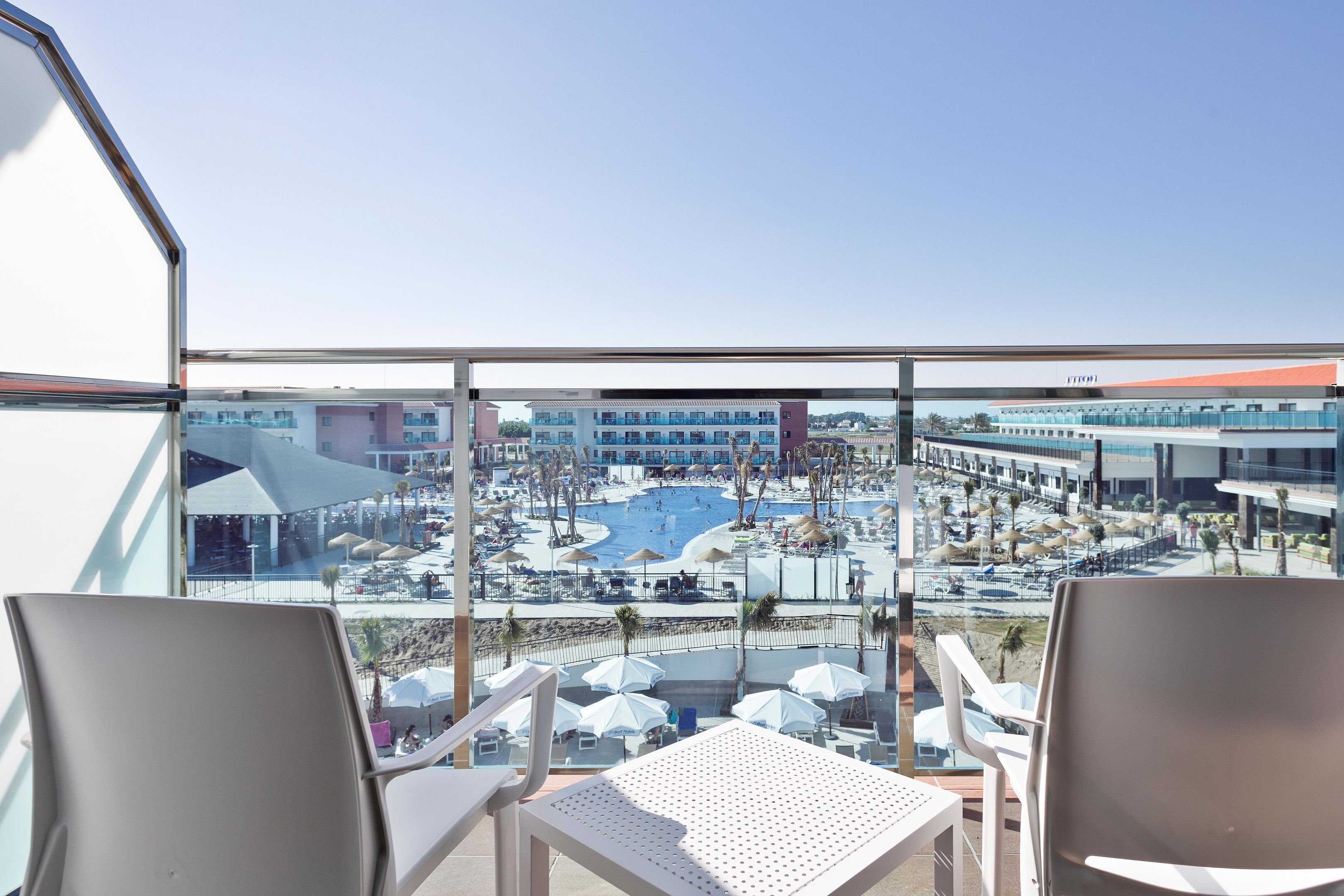 A balcony with a view of a swimming pool and a hotel building.