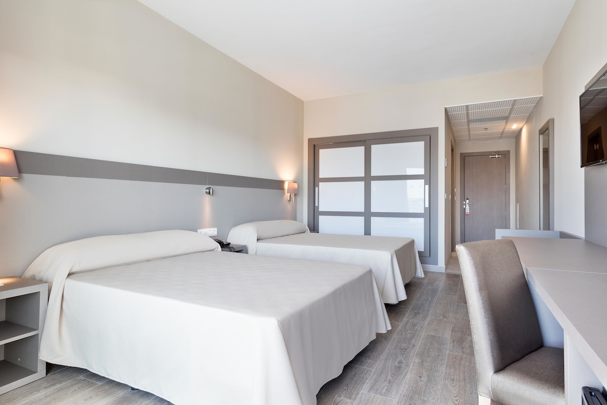 Ein Hotelzimmer mit zwei Betten, einem Schreibtisch und einem Sessel.