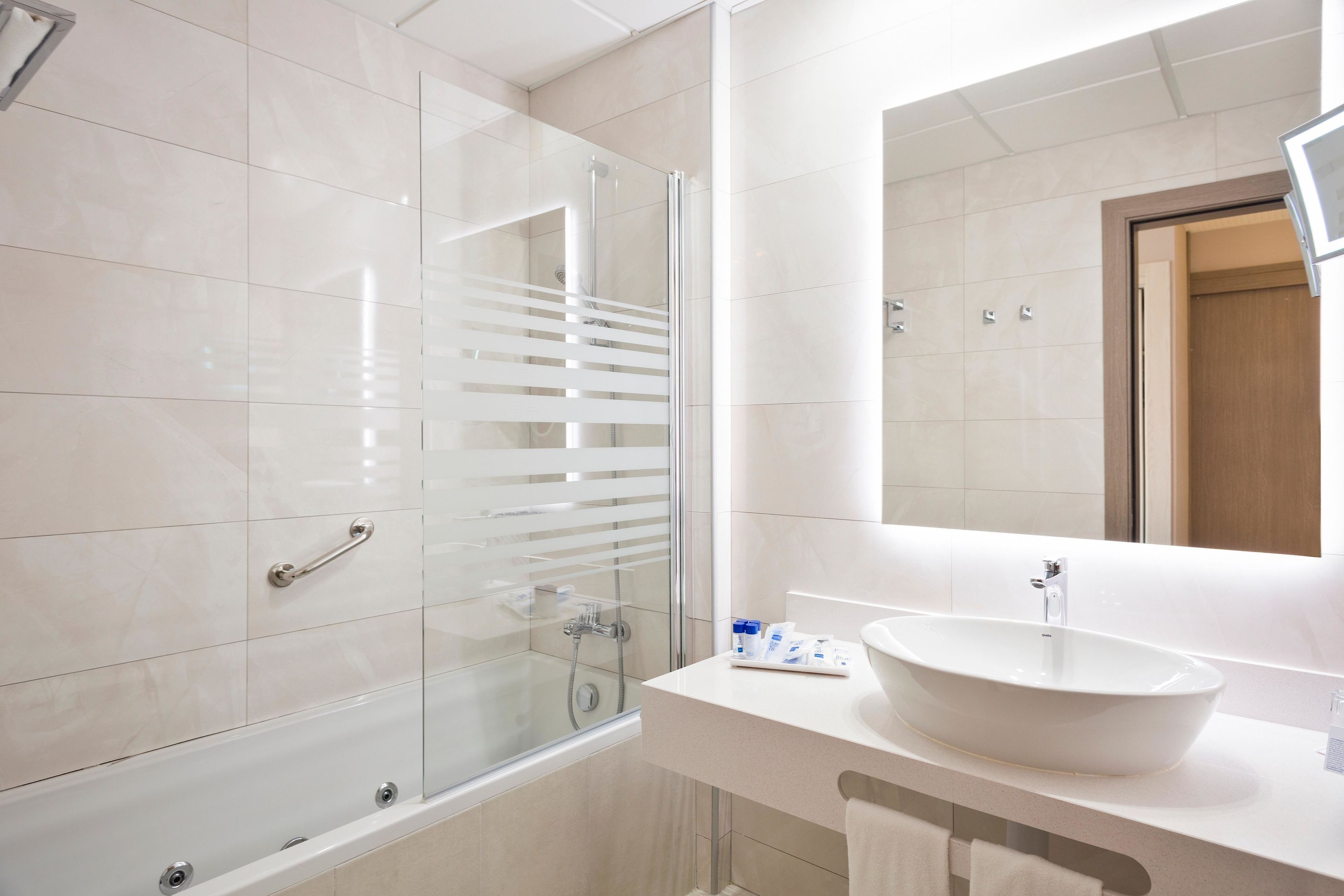 A modern bathroom with a glass-enclosed shower, a white sink, and a large mirror.