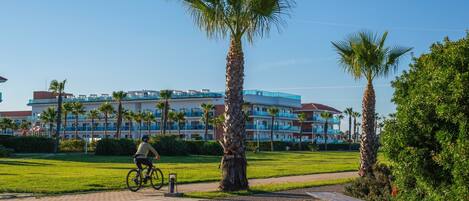 A hotel with a modern design, featuring a large building with multiple balconies and palm trees in the foreground.