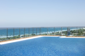Una piscina infinita en la azotea con vistas despejadas al océano y a la playa.