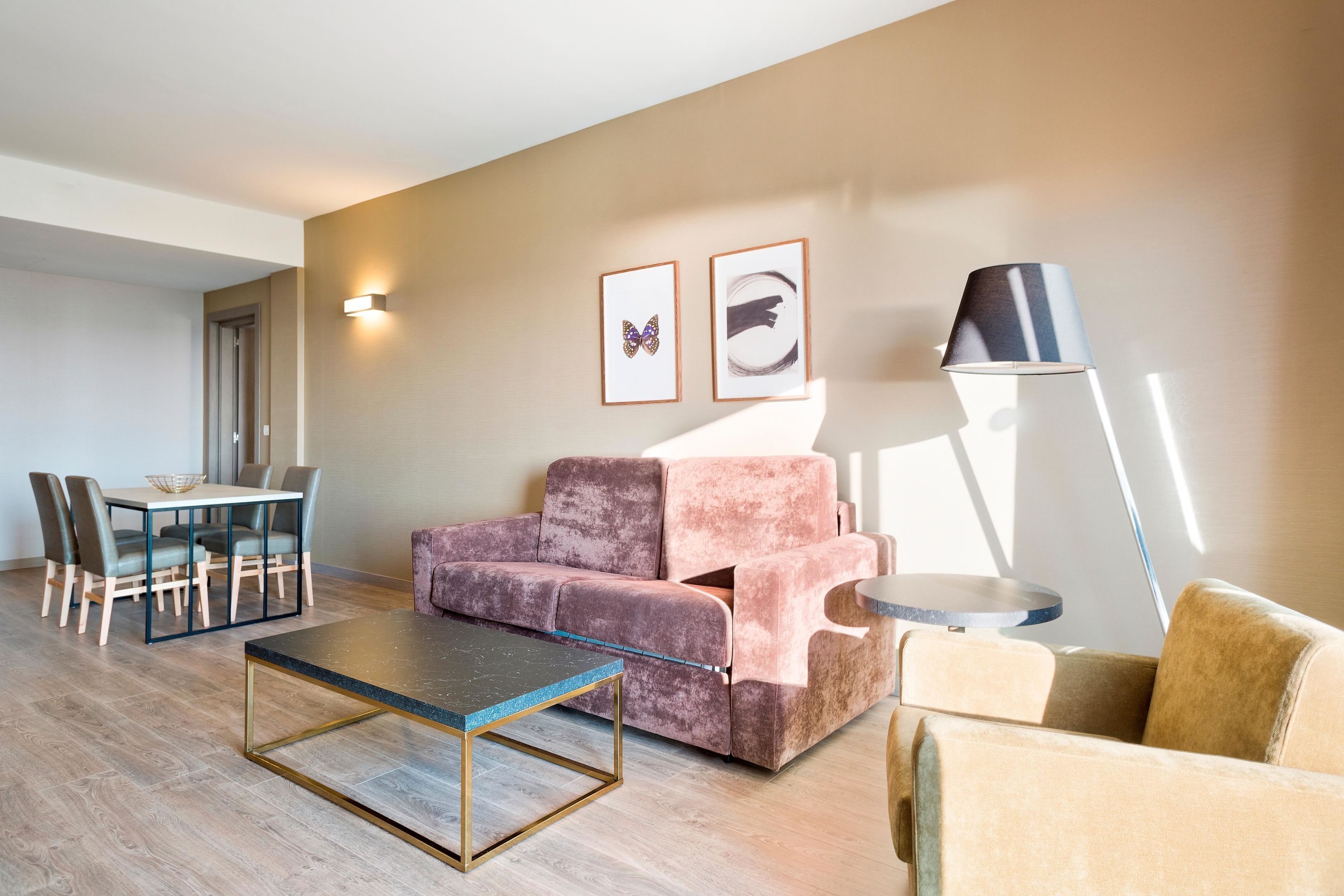 A modern living room with a sofa, a coffee table, and a dining area with chairs and a table.