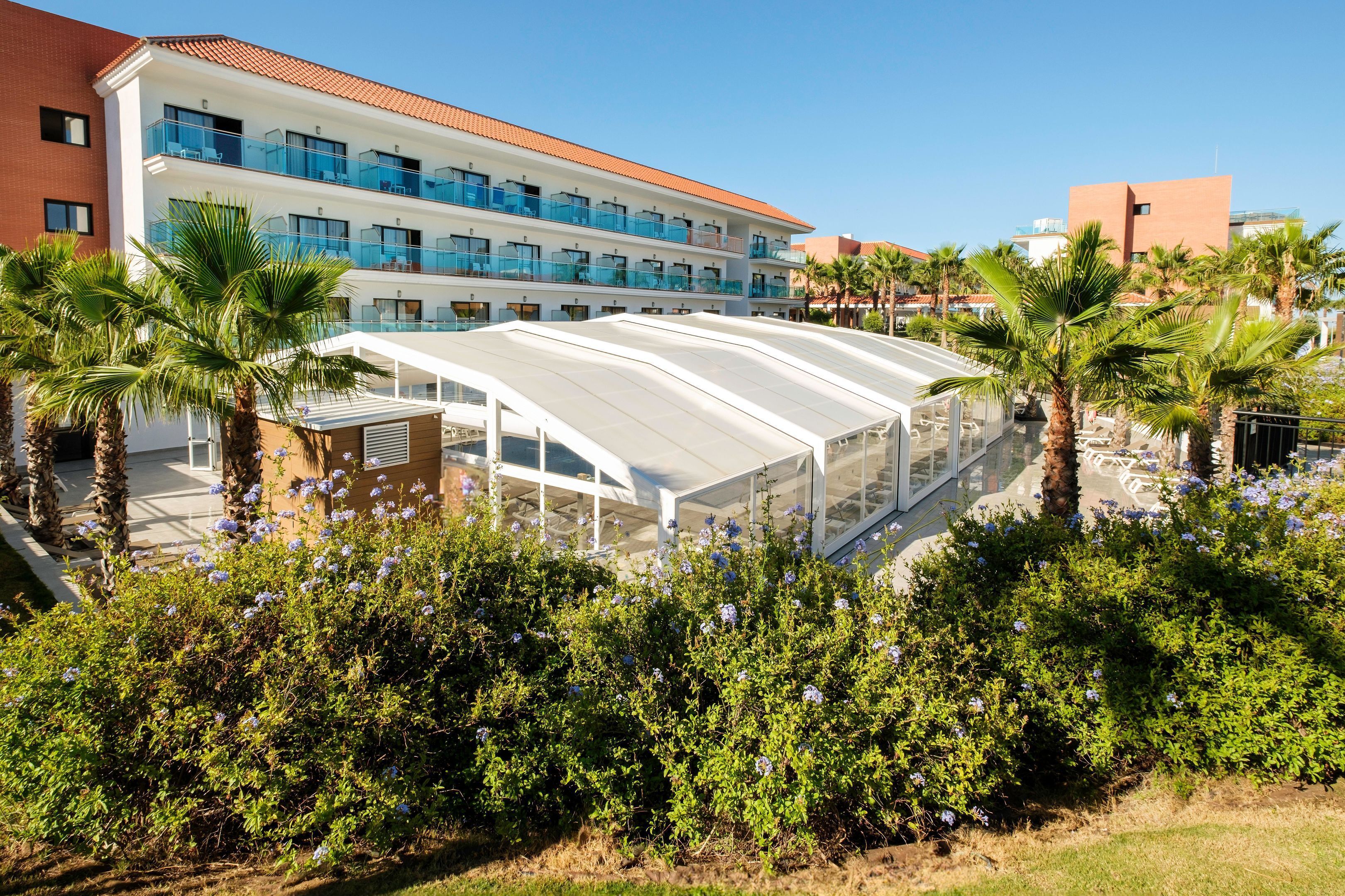 A hotel with multiple balconies, a covered walkway, and palm trees.