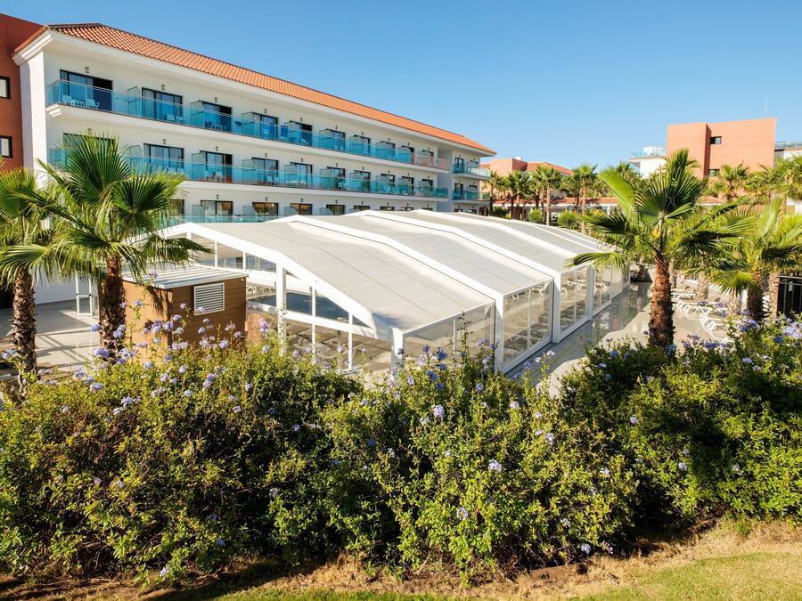 A hotel with multiple balconies, a covered walkway, and palm trees.