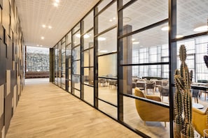 A modern interior with a wooden floor, glass partitions, and a cactus in a glass vase.