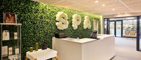 A reception area with a green wall, a white reception desk, and a seating area with chairs.