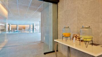 A modern hotel lobby with a glass wall, a reception desk, and two large water dispensers.