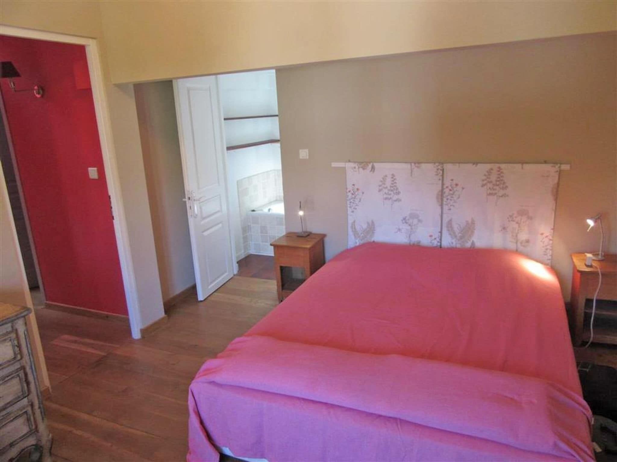 Ein Schlafzimmer mit einem Bett, einem Nachttisch, einer Kommode und einer roten Tür.