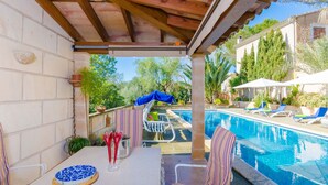 Ein überdachter Außenbereich mit Pool, Liegestühlen und einem Tisch mit Teller und Besteck.