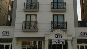 Hotellin edessä on kyltti, jossa lukee: ”CITY HOTEL” ja ”Plus City Cafe-Rub”.