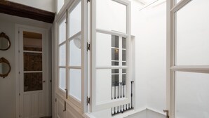 Una stanza con una grande finestra, una porta con uno specchio e un pavimento decorato.