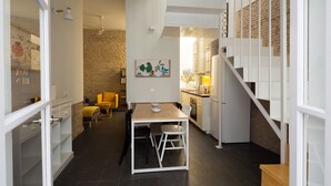 Una cucina moderna con zona pranzo, una scala e un muro in mattoni.