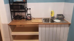 Uma cozinha compacta com micro-ondas, torradeira e pia.