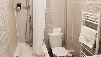 A modern bathroom with a bathtub, toilet, and shower.