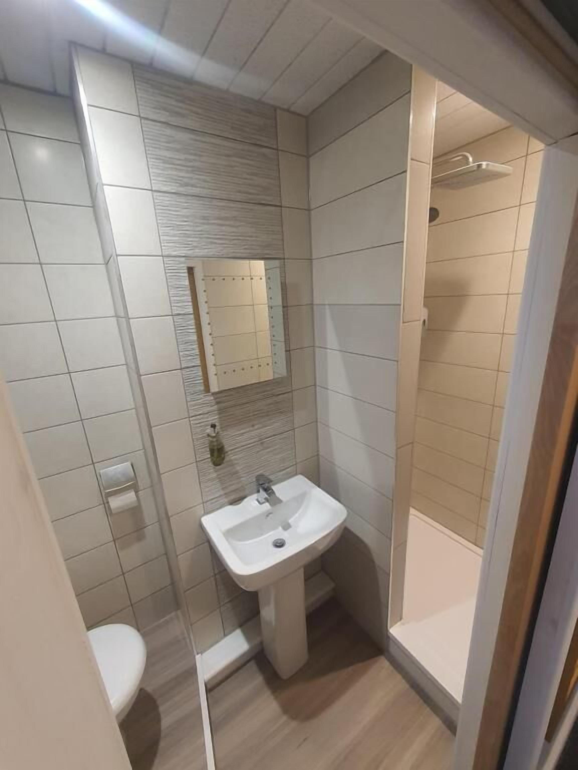 A bathroom with a toilet, sink, and shower.