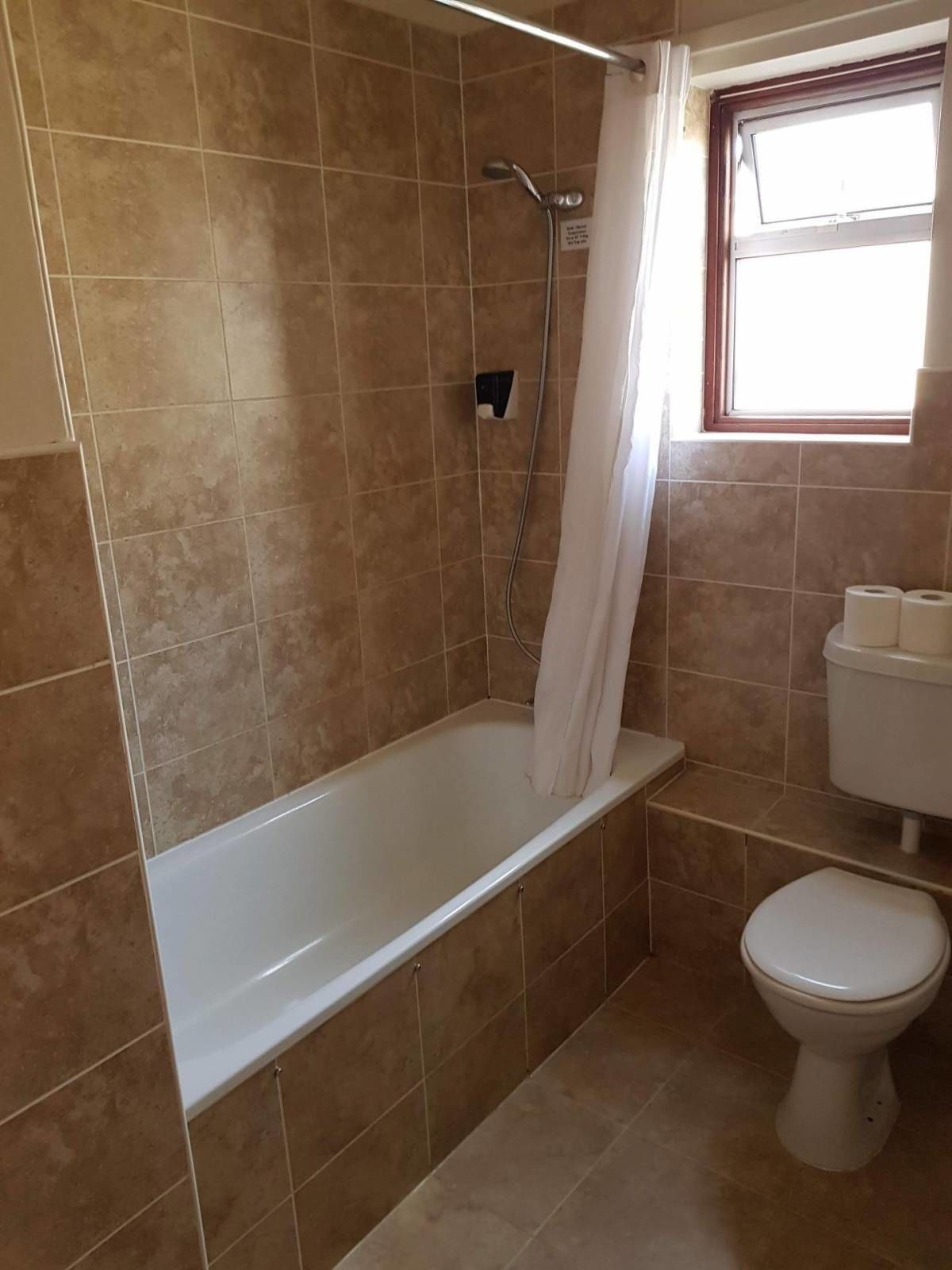 Un baño con bañera, inodoro y ventana.